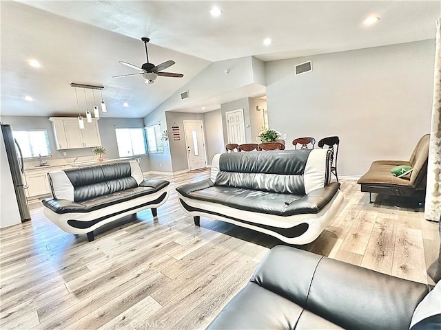 living room with ceiling fan, vaulted ceiling, sink, and light hardwood / wood-style flooring