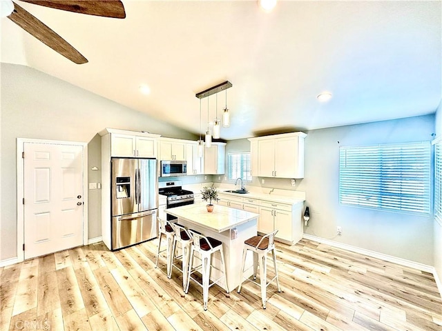 kitchen featuring a center island, sink, hanging light fixtures, appliances with stainless steel finishes, and white cabinets