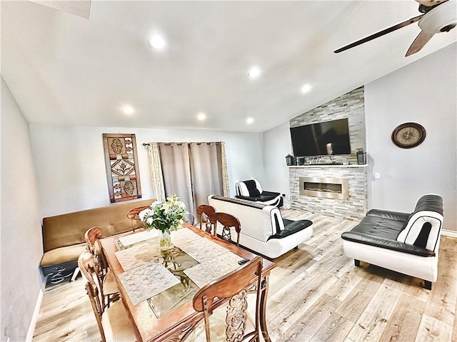 dining area with light wood-type flooring, ceiling fan, lofted ceiling, and a fireplace