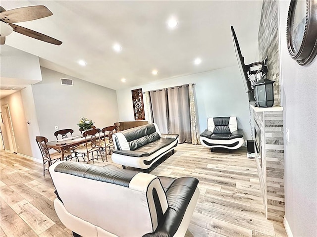 living room featuring ceiling fan, lofted ceiling, and light hardwood / wood-style flooring