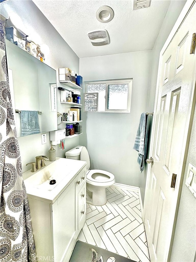 bathroom with a textured ceiling, toilet, and vanity