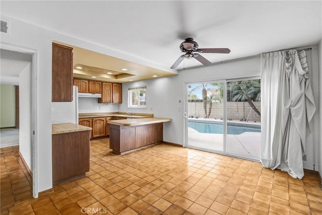 kitchen featuring ceiling fan, kitchen peninsula, and a raised ceiling