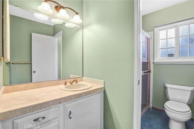 bathroom featuring vanity, a shower with shower door, and toilet