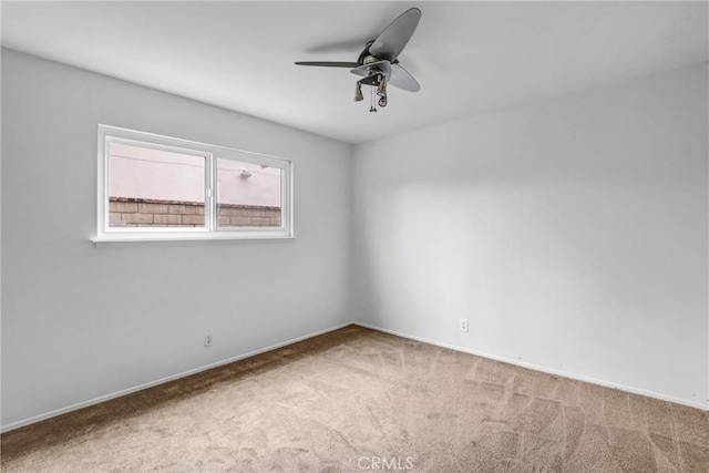 spare room featuring carpet floors, a ceiling fan, and baseboards