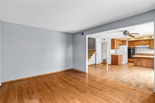 unfurnished living room featuring ceiling fan and light hardwood / wood-style flooring