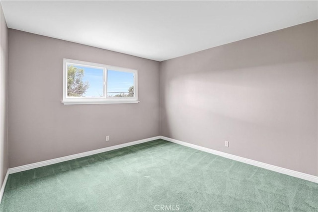 carpeted spare room featuring baseboards