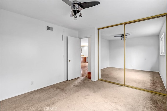 unfurnished bedroom featuring ceiling fan, a closet, carpet flooring, and visible vents