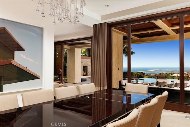 dining area featuring an outdoor fireplace, a water view, and a chandelier