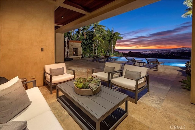 patio terrace at dusk featuring an outdoor living space with a fireplace