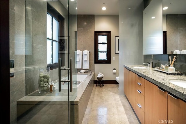 bathroom featuring vanity, toilet, a wealth of natural light, and tiled tub