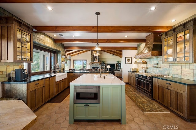 kitchen featuring range with gas cooktop, a center island with sink, beam ceiling, sink, and hanging light fixtures