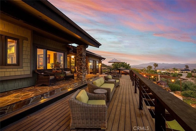 deck at dusk featuring a mountain view and an outdoor living space