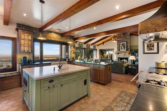 kitchen with premium range hood, ceiling fan, a kitchen island with sink, a fireplace, and hanging light fixtures