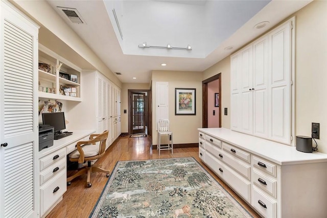 office with built in desk and light hardwood / wood-style floors