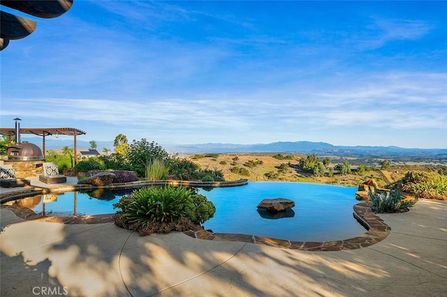 view of pool featuring a mountain view, exterior kitchen, and a patio