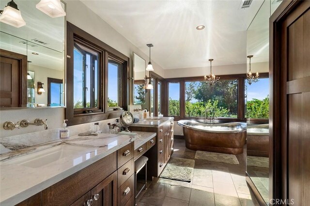 bathroom featuring a tub, tile patterned floors, vanity, and an inviting chandelier