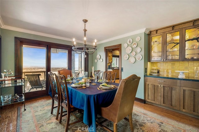 dining room with light hardwood / wood-style flooring, ornamental molding, and an inviting chandelier