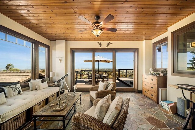 sunroom featuring ceiling fan, wooden ceiling, and a wealth of natural light