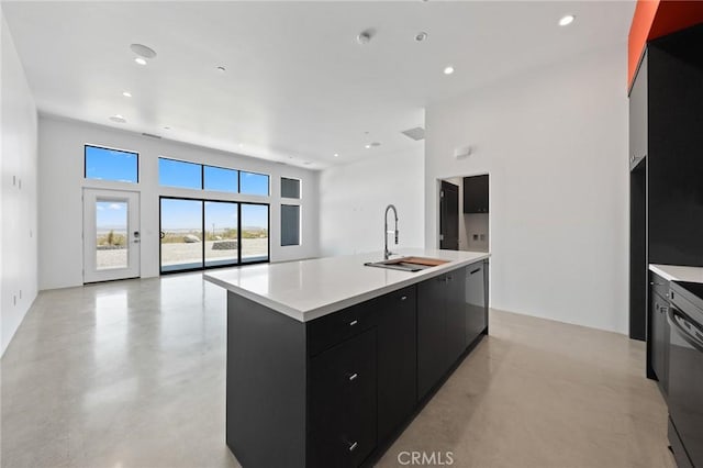 kitchen with dishwashing machine, sink, dishwasher, and a center island with sink