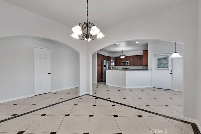 interior space featuring stainless steel appliances, hanging light fixtures, a notable chandelier, light tile patterned floors, and dark brown cabinets