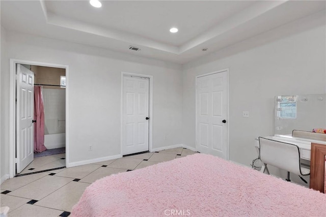 tiled bedroom featuring a raised ceiling and ensuite bath