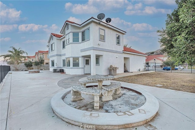 rear view of house with cooling unit and a fire pit