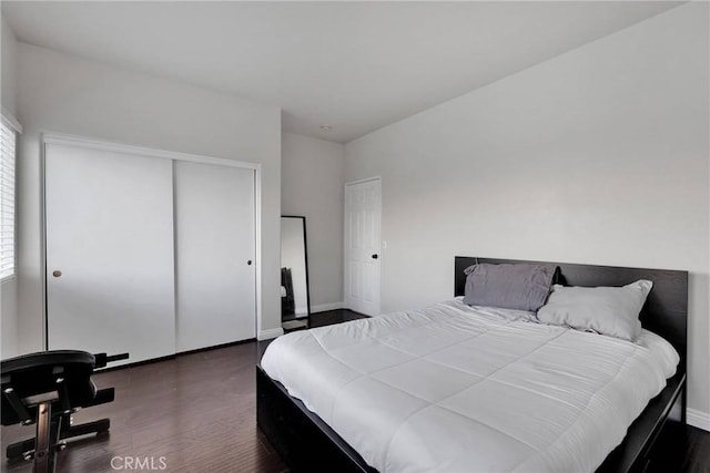 bedroom featuring multiple windows, dark hardwood / wood-style floors, and a closet