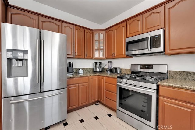 kitchen featuring light tile patterned floors, stainless steel appliances, and dark stone countertops