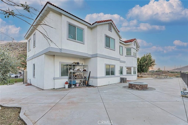 rear view of house featuring central AC unit, a patio area, and a fire pit