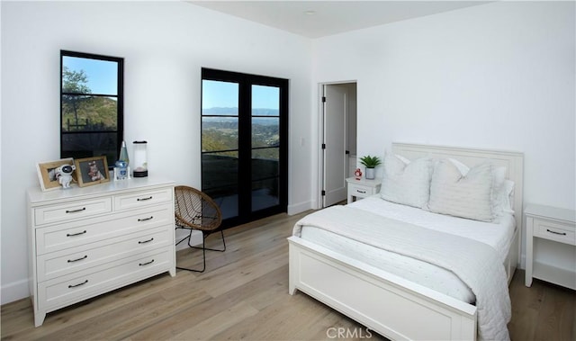 bedroom featuring access to exterior, french doors, and light hardwood / wood-style flooring