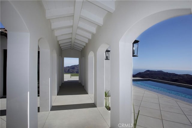 corridor featuring light tile patterned floors, a mountain view, and lofted ceiling with beams