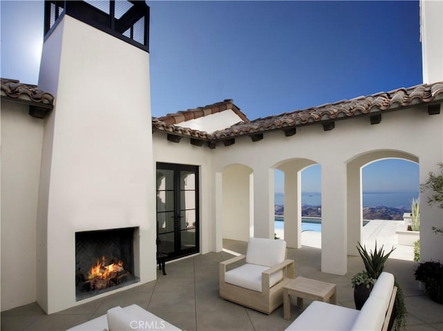 view of patio with a water view and an outdoor fireplace