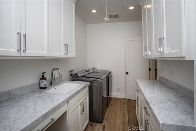 laundry area with light wood-type flooring, independent washer and dryer, sink, and cabinets