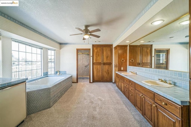 bathroom with a textured ceiling, vanity, backsplash, ceiling fan, and independent shower and bath