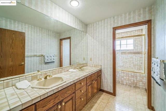 bathroom featuring tiled bath, vanity, and a textured ceiling