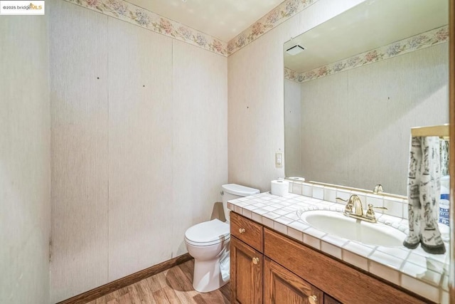 bathroom with wood-type flooring, toilet, and vanity