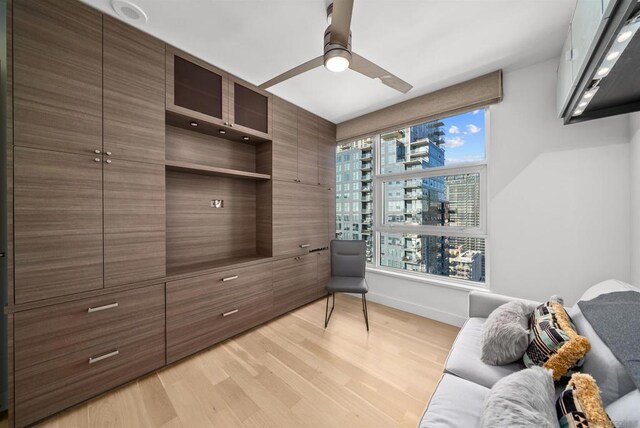 living area with light hardwood / wood-style floors and ceiling fan