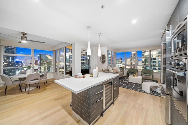 kitchen with a center island, wine cooler, light hardwood / wood-style floors, oven, and ceiling fan