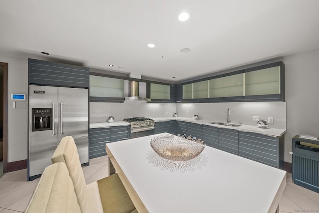 kitchen with light tile patterned floors, premium appliances, sink, and wall chimney exhaust hood