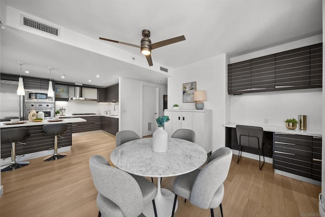 dining room featuring ceiling fan, sink, and light wood-type flooring