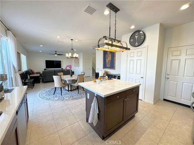 kitchen featuring pendant lighting, ceiling fan, light tile patterned floors, a kitchen island, and dark brown cabinetry