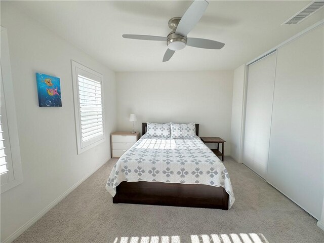 carpeted bedroom with ceiling fan and a closet