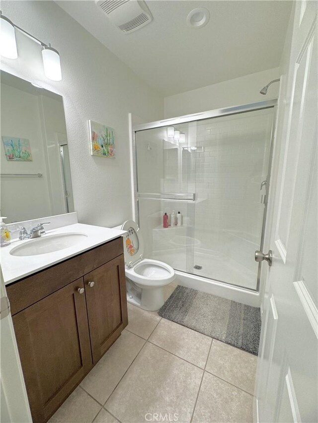 bathroom with vanity, toilet, a shower with shower door, and tile patterned flooring