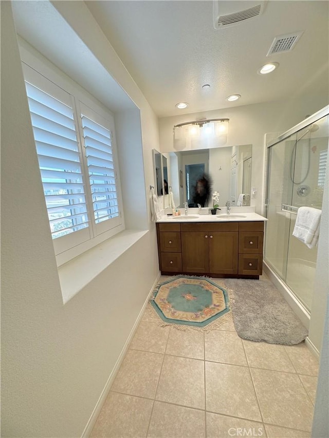 bathroom featuring a shower with shower door, vanity, and tile patterned flooring