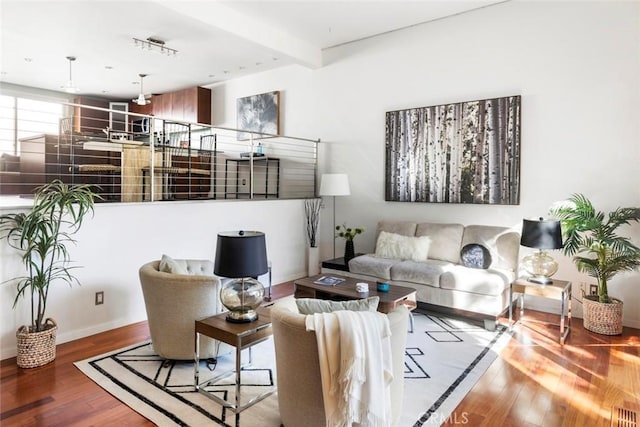 living room featuring beamed ceiling and hardwood / wood-style flooring