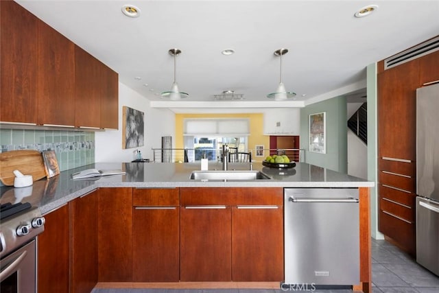 kitchen with appliances with stainless steel finishes, decorative light fixtures, tasteful backsplash, sink, and kitchen peninsula