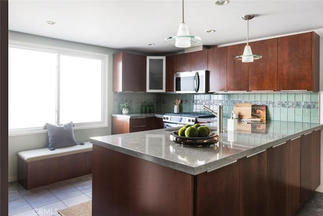 kitchen featuring dark stone counters, light tile patterned flooring, stainless steel appliances, and pendant lighting