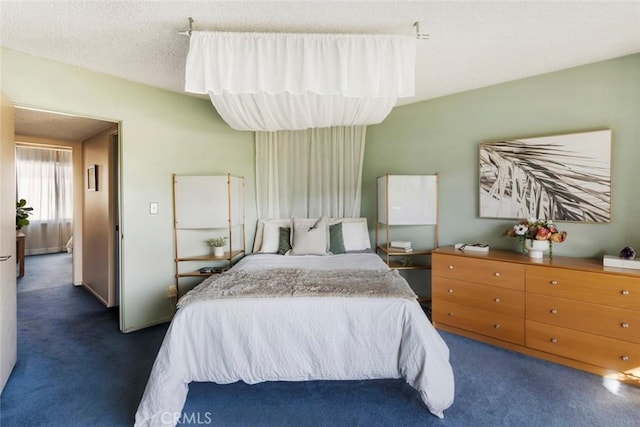 bedroom featuring dark carpet and a textured ceiling