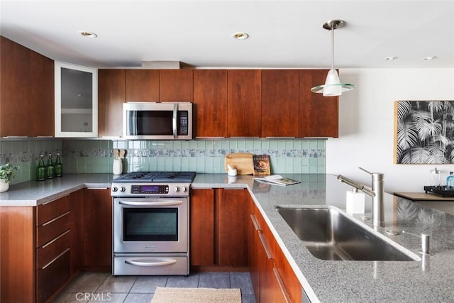 kitchen featuring decorative light fixtures, stainless steel appliances, sink, backsplash, and light tile patterned floors