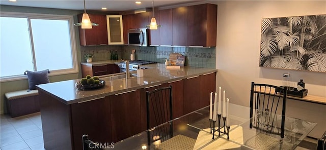 338 N Clybourn Ave, Burbank, CA 91505 - kitchen featuring stainless steel microwave, decorative backsplash, light tile patterned floors, glass insert cabinets, and decorative light fixtures